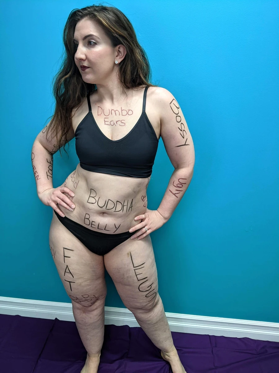 Woman displaying hurtful words written on body in a body image fitness program