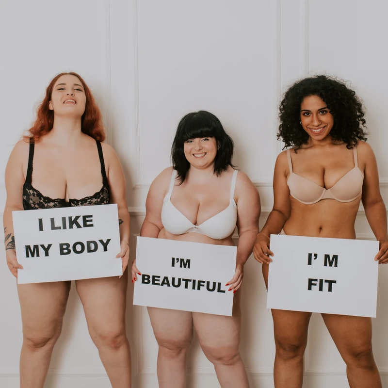 Woman holding signs about their body positive fitness journey